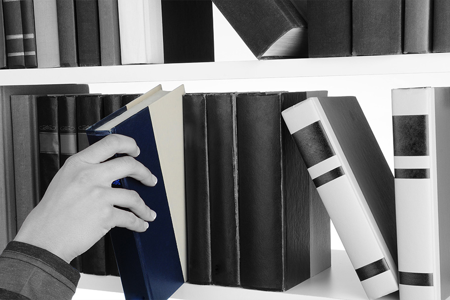 Eine Person nimmt sich ein farblich hervorgehobenes Buch von einem Regal – Rohnstock Biografien